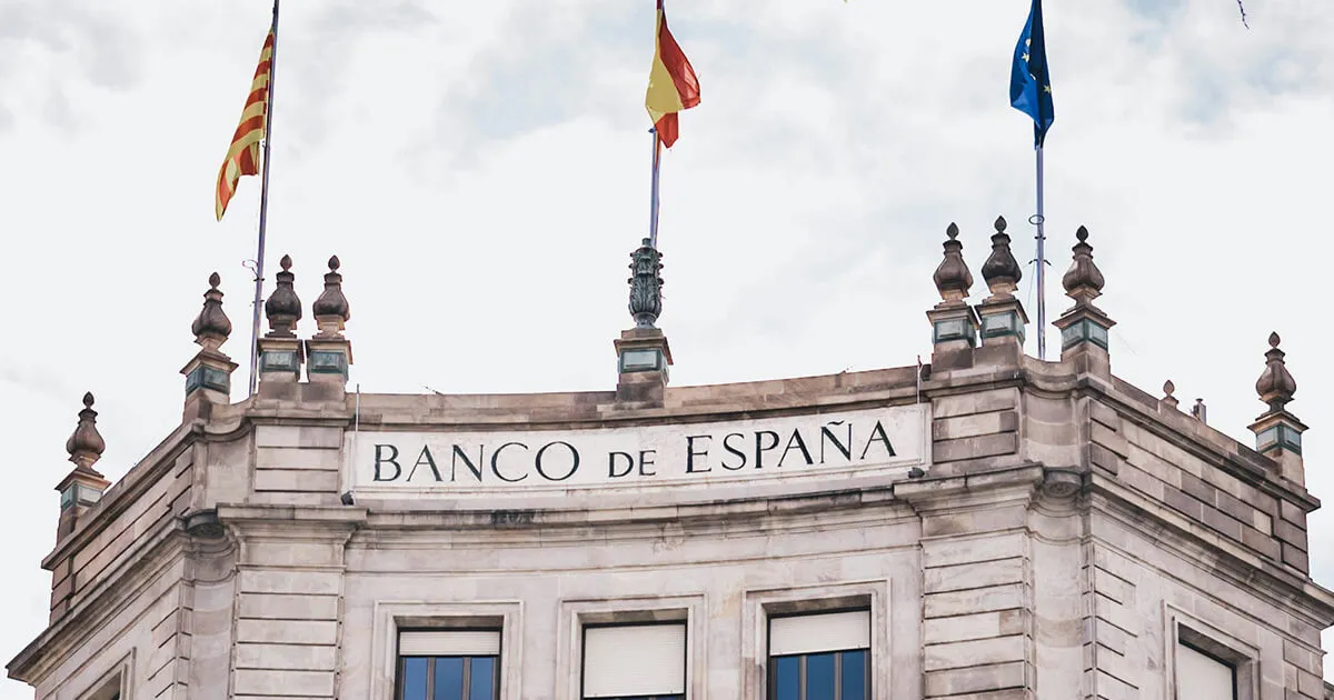 A Spanish bank card and bank statement on a wooden desk with a coffee cup