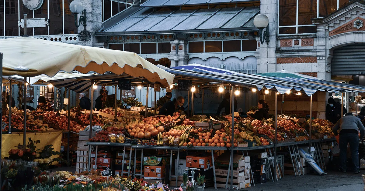 A colourful French outdoor market with fresh produce, cheese and charcuterie stalls