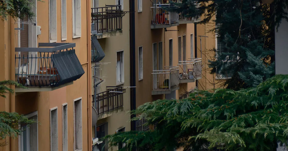 Un immeuble d'appartements dans une ville italienne avec une pancarte d'agence immobilière et des balcons ornementaux